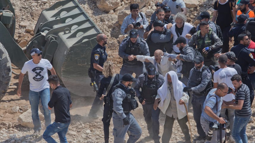 Israel Border Police confront protesters and activists blocking an IDF bulldozer operating in Khan al-Ahmar, June 9, 2019.Credit: Nasser Nasser / AP