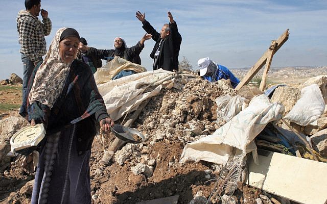 Illustrative: Palestinians try to retrieve items from the rubble of a house after it was destroyed by IDF tractors near the West Bank village of Sussiya in 2011. (Najeh Hashlamoun/ Flash90)
