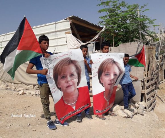 Children in Khan al-Ahmar hold posters of German Chancellor Angela Merkel saying “Save Khan al Ahmar” on Tuesday, Oct. 2 (Photo Courtesy of Jamal Saifan)