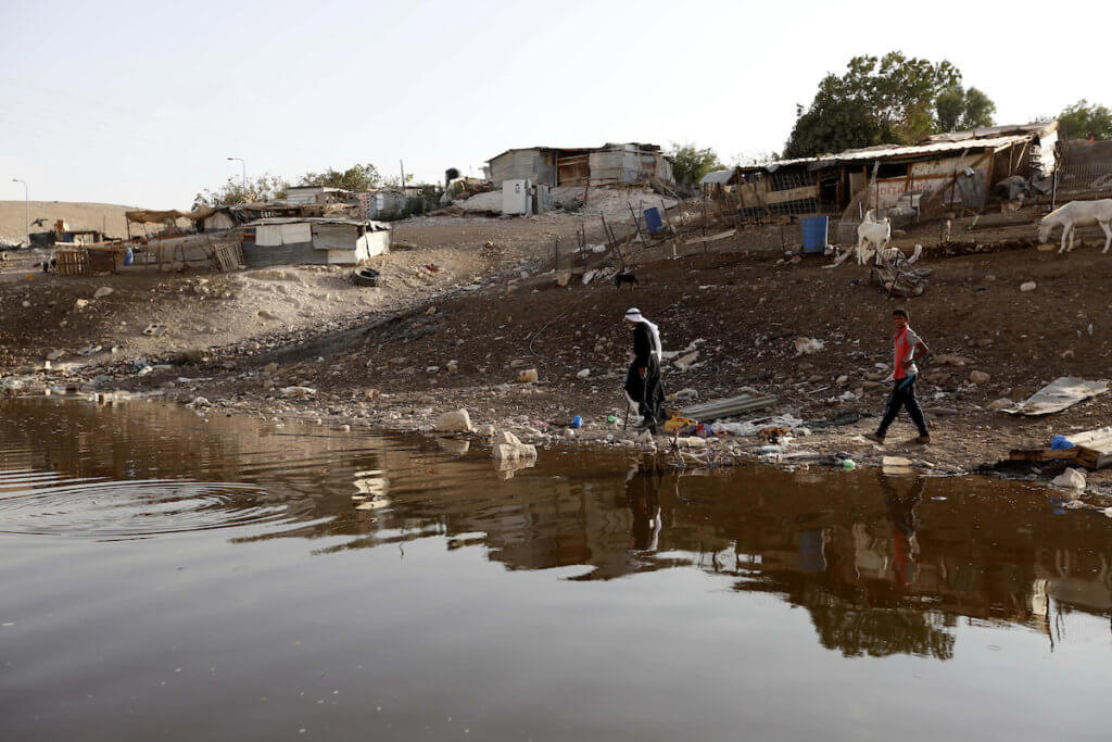 Palestinians walk near a wastewater pond, at the Palestinian Bedouin village of Al Khan al-Ahmar which Israel plans to demolish, in the West Bank on October 2, 2018. (Photo: Wisam Hashlamoun/APA