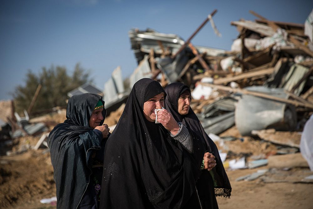 Bedouin women collect their belongings from the ruins of their demolished homes in the unrecognized village of Umm al-Hiran in the Negev desert, in the in the Southern Israel, January 18, 2017. (Hadas Parush/Flash90)