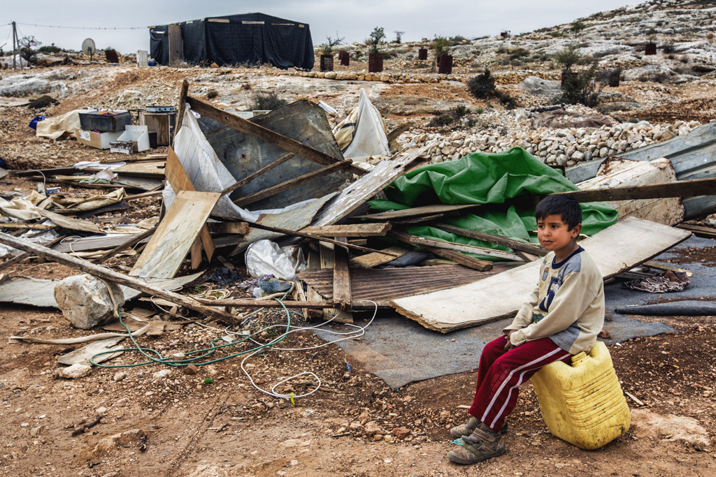 A boy sits a top a water can in front of the ruins of his family home, which was destroyed the day before. Dec. 28, 2013. West Bank, Palestinian Territories. (Photo by Gabriel Romero/Alexia Foundation ©2014)