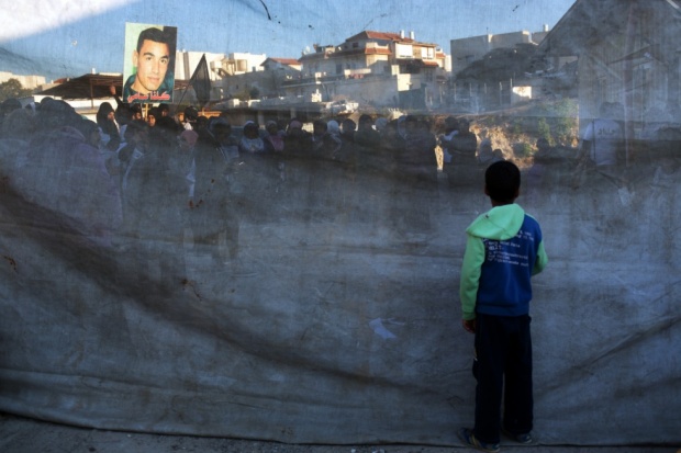 A boy watches through a cloth as protesters march in the Bedouin town of Rahat after the killing of two locals by Israeli forces (AFP)